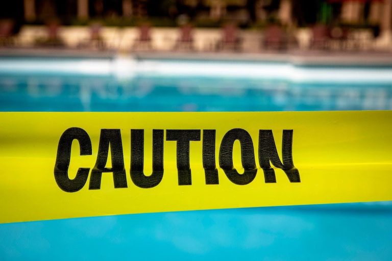 Yellow caution tape in front of swimming pool.