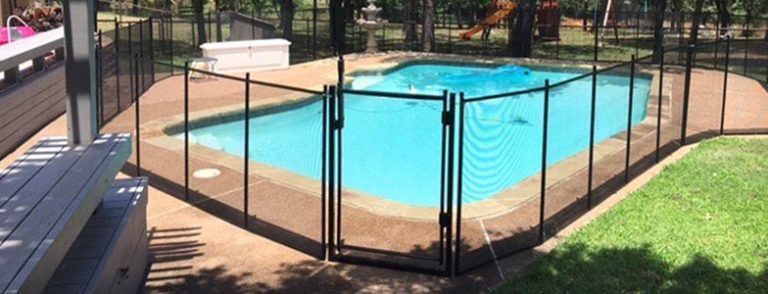 A pool fence with a secure gate around a pool in Branson, surrounded by grass, a playground, and other backyard features.