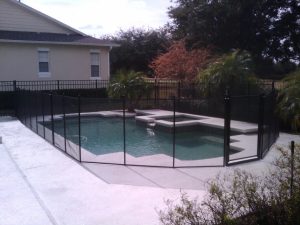Black mesh pool fence surrounding backyard geometric shaped pool in Lakeland Florida