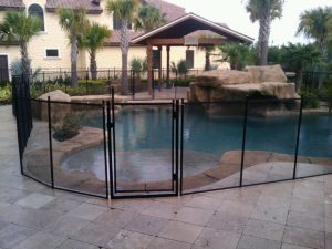 Black mesh pool fence installed around rock-style pool in Lakeland backyard