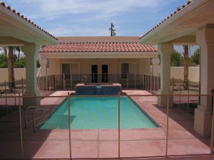 Enclosed courtyard pool with an Inland Empire pool fence in front of a house with a red-tiled roof.