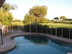Serene poolside view with a pool fence in the Inland Empire, surrounded by lush greenery and a clear blue pool.