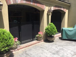 Mesh safety fence installed around patio entrances with potted plants, lantern-style lights, and covered outdoor furniture in Tulsa, OK.