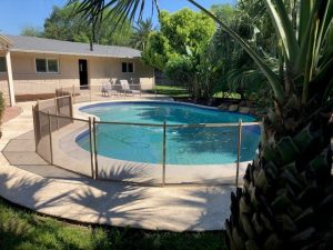 Tan mesh pool fence enclosing kidney-shaped backyard pool in Houston, Texas