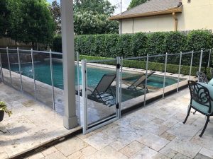 Modern white mesh pool fence with safety gate around rectangular backyard pool in Houston, TX