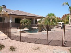 Brown mesh pool fence around desert-style backyard pool in Houston, TX