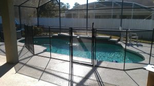 Mesh pool fence installation surrounding a free form shaped backyard pool in Orlando FL