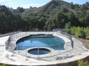 Backyard pool in Ventura with a curved black mesh pool fence enclosure