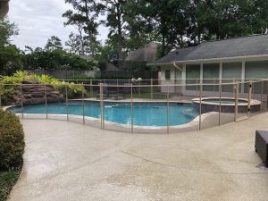 Tan pool safety fence installed around residential pool and spa in Houston backyard