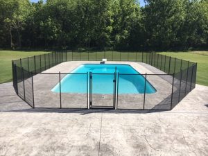 Rectangular pool fence installation in Tulsa with a black safety fence surrounding a rectangular swimming pool on a concrete patio.