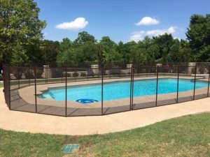 Round pool fence installation in Tulsa showing a black safety fence surrounding a circular swimming pool on a sunny day.