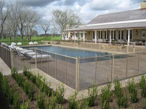 Large rectangular safety pool fence installation at a Houston estate with modern patio layout
