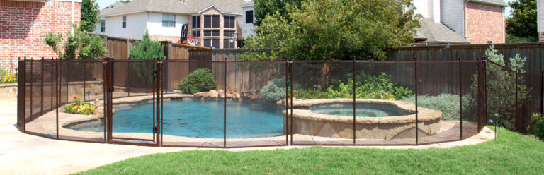 A kidney-shaped pool in Pequannock surrounded by a beige mesh pool fence with a potted plant placed near the water. The fence is positioned securely around the pool, with a safety barrier, and plants visible in the background.