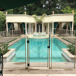 Elegant beige mesh pool fence with secure gate enclosing luxury swimming pool in Bahamas