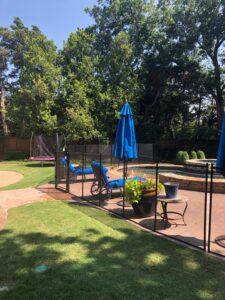 Black mesh pool fence with secure gate installed around backyard pool in Canada with blue loungers and umbrellas