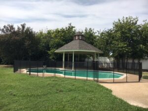 Secure black mesh pool fence installed around a residential pool in Dallas with a central gazebo