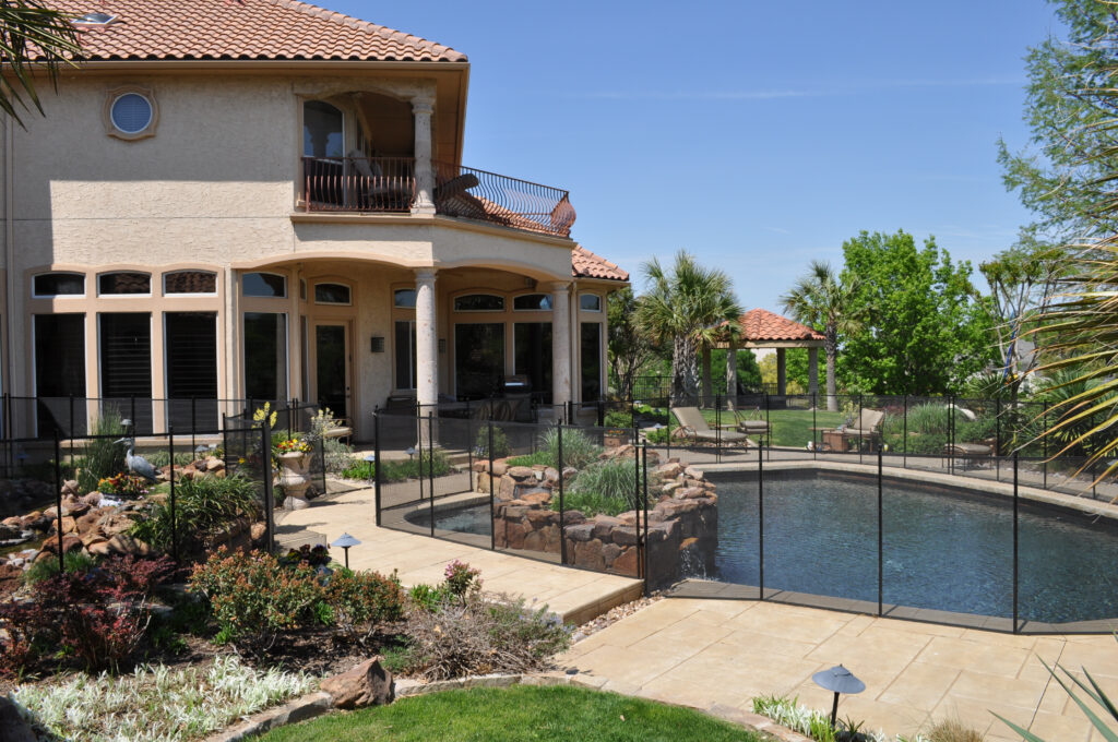 Luxury California home with pool secured by removable mesh safety fence and landscaped garden