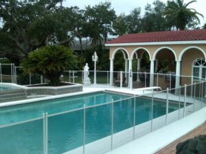 White mesh pool safety fence installed around a pool with a Mediterranean-style gazebo in the background